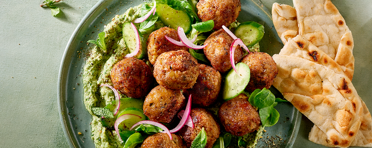 Hälsans Kök Vegan Balls served over hummus with vegetables and herbs