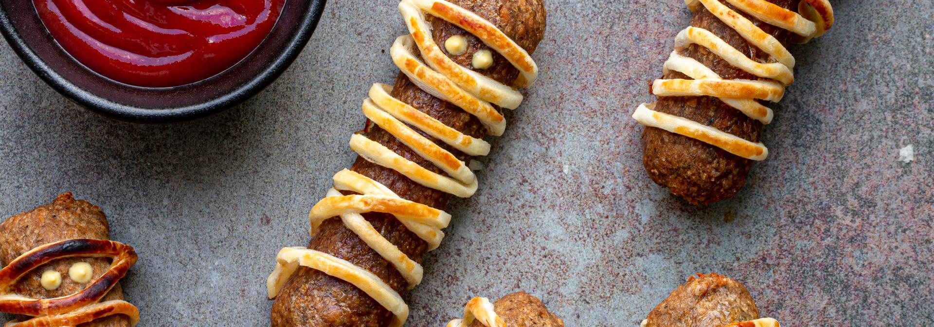 Sausages covered in puffed pastry looking like mummies