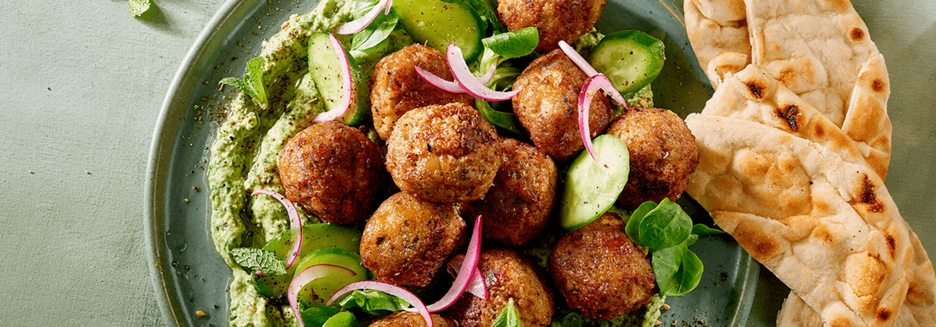 Hälsans Kök Vegan Balls served over hummus with vegetables and herbs